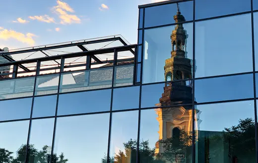 Lustrzane odbicie wieży Kościoła Franciszkanów w przeszklonej fasadzie nowoczesnego budynku przy Placu Bernardyńskim w Poznaniu | Fot. ks. Wojciech Nowicki