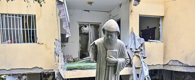 Figura św. Szarbela, maronickiego duchownego, mnicha i pustelnika, przed zniszczonym w izraelskim ataku budynkiem mieszkalnym w zamieszkanym głównie przez chrześcijan mieście Ain Saadeh nieopodal Bejrutu, 6 kwietnia 2026 r.